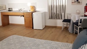 Cozinha compacta com geladeira, micro-ondas e chaleira.