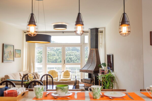 Un espace repas doté d’une grande fenêtre, d’une cheminée et de luminaires suspendus.