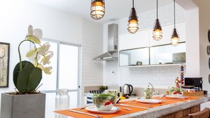 A modern kitchen with a marble countertop, hanging pendant lights, and a potted orchid. - Incrível Vista com 4 Quartos e Lareira (Campos do Jordão)