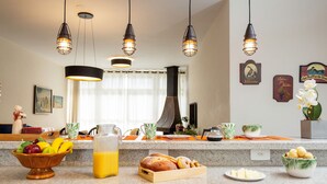 A kitchen counter with breakfast items, a fruit bowl, and a coffee maker. - Incrível Vista com 4 Quartos e Lareira (Campos do Jordão)