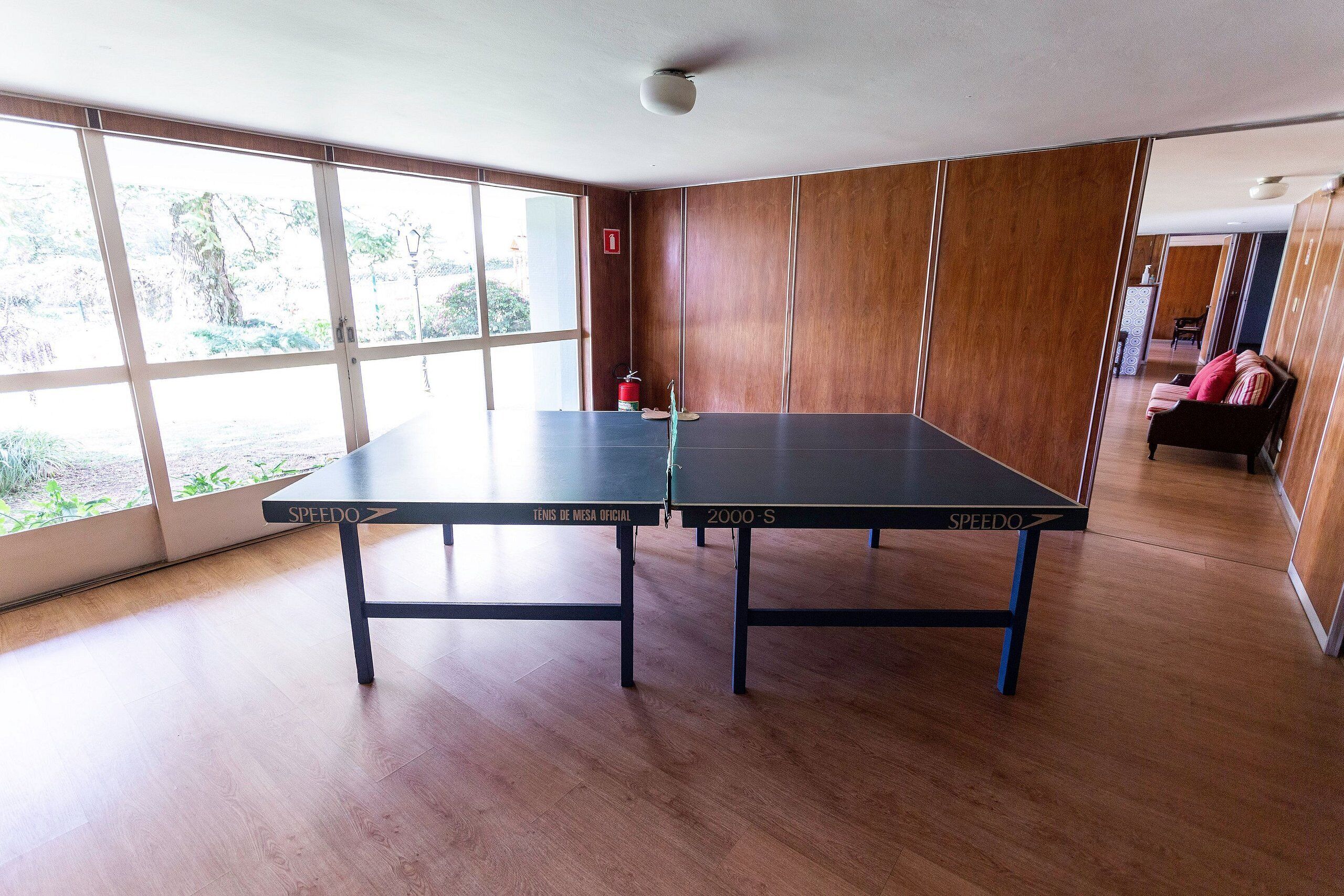 Une pièce équipée de deux tables de ping-pong Speedo, de grandes fenêtres et offrant une vue sur l’extérieur.