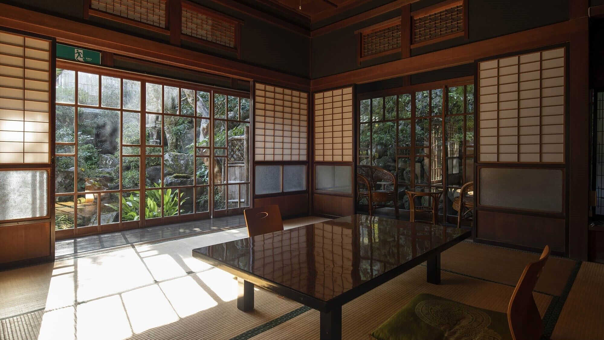 Una habitación tradicional japonesa con suelo de tatami, una mesa baja y puertas correderas.