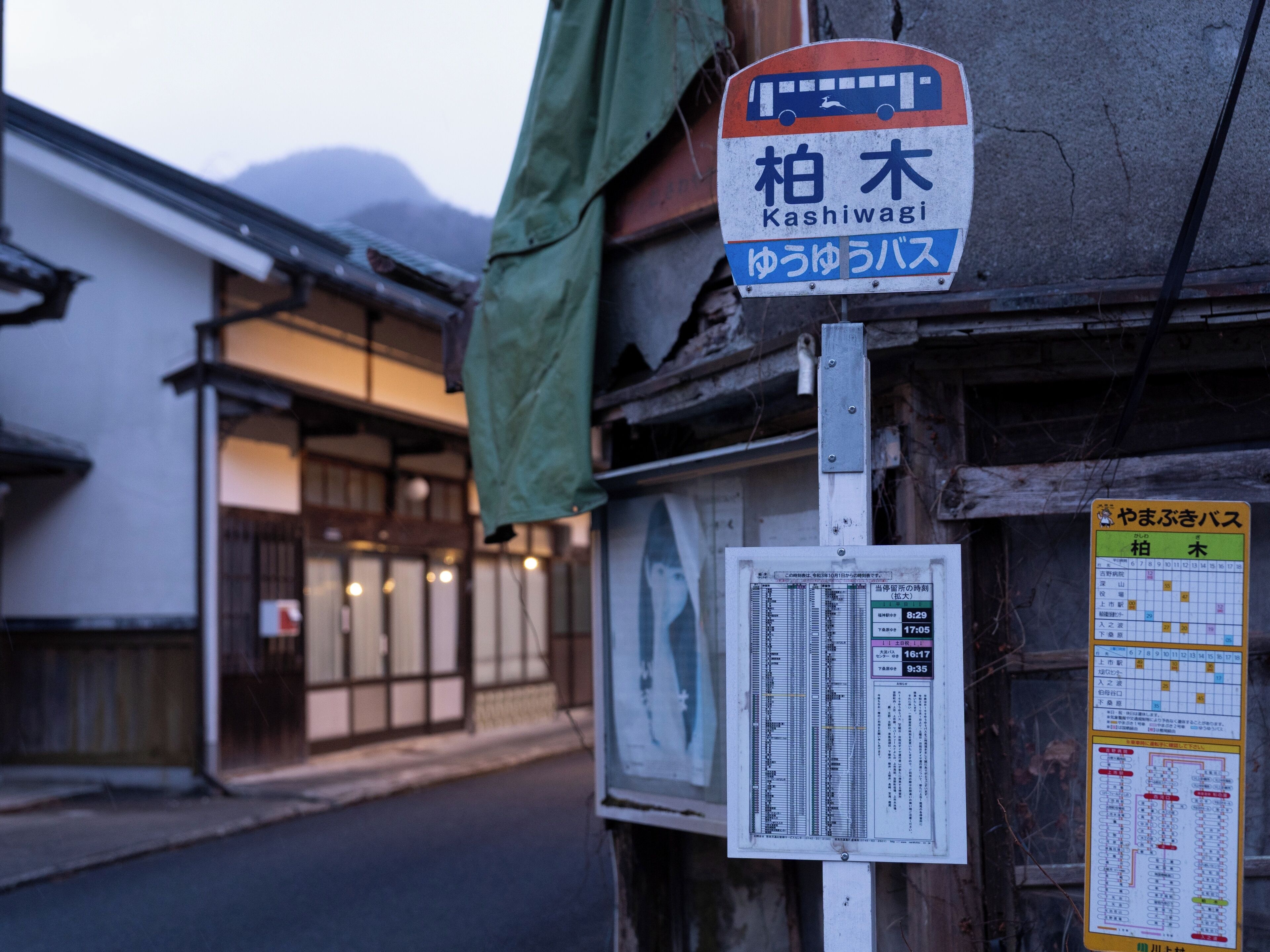 A bus stop sign with Japanese text and a bus timetable.
