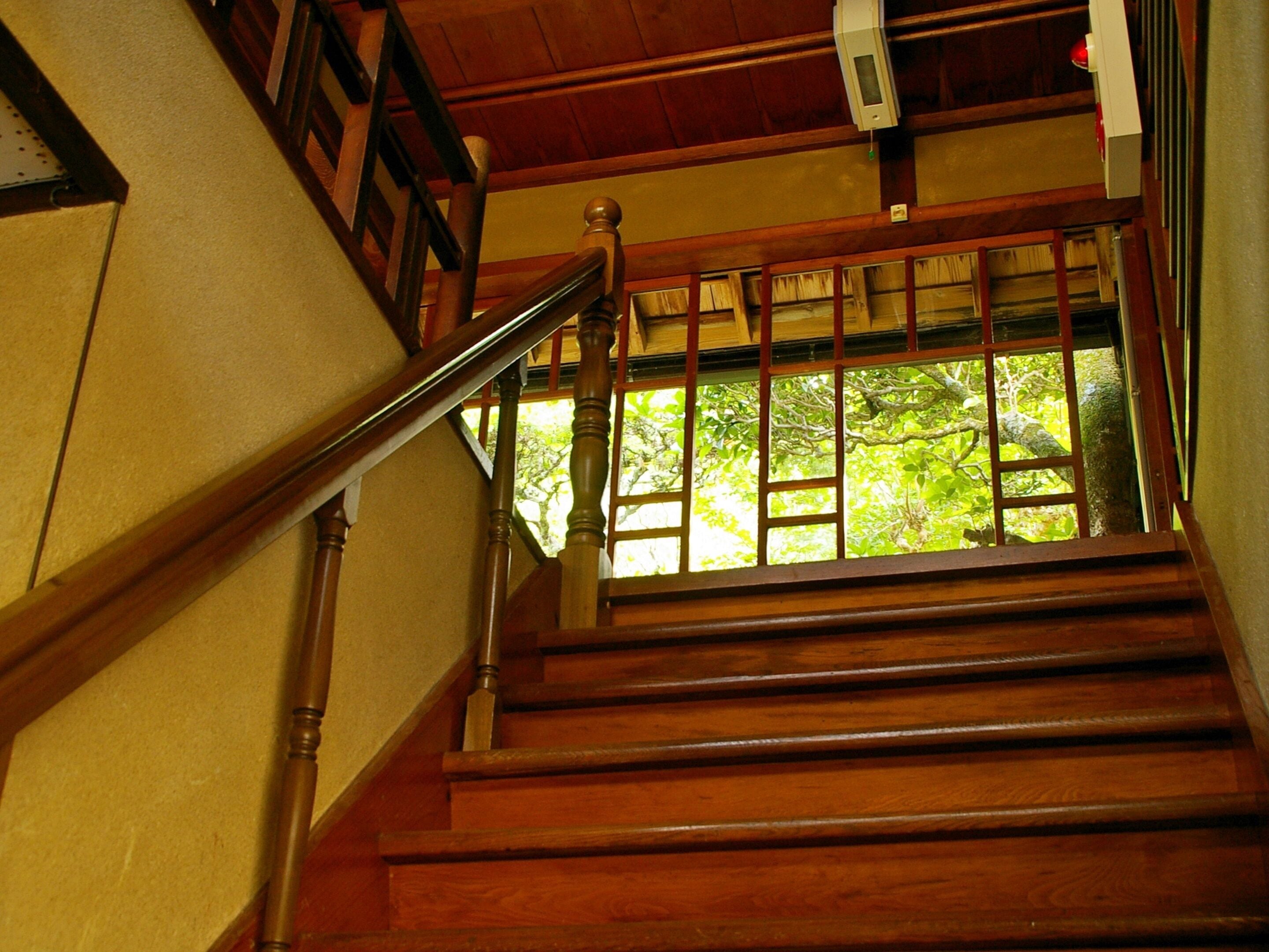 A wooden staircase with a handrail and a window at the top.