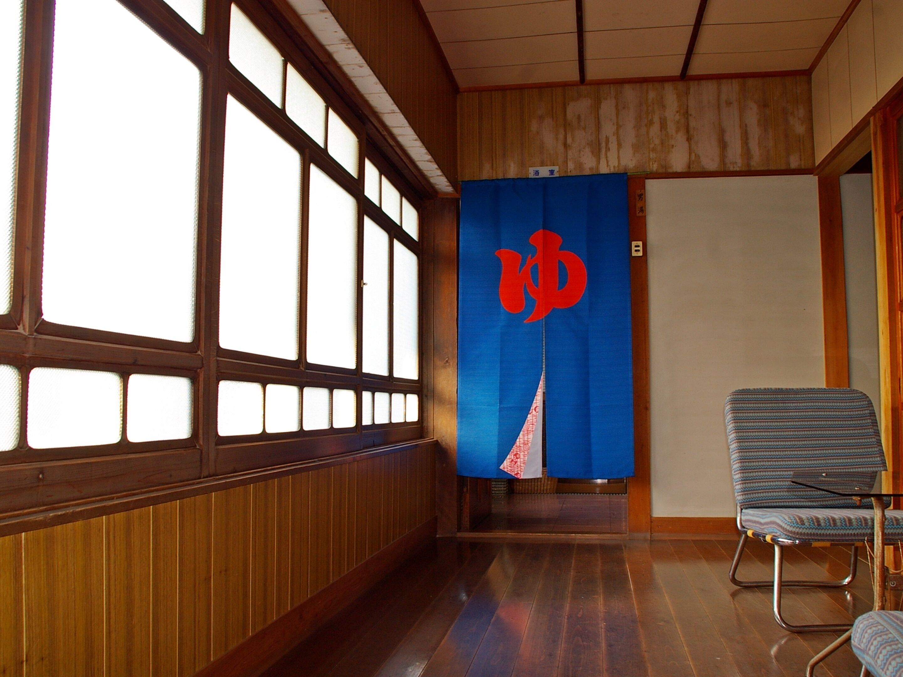Un pasillo con paneles de madera, una cortina azul con un logotipo rojo y una silla estampada.