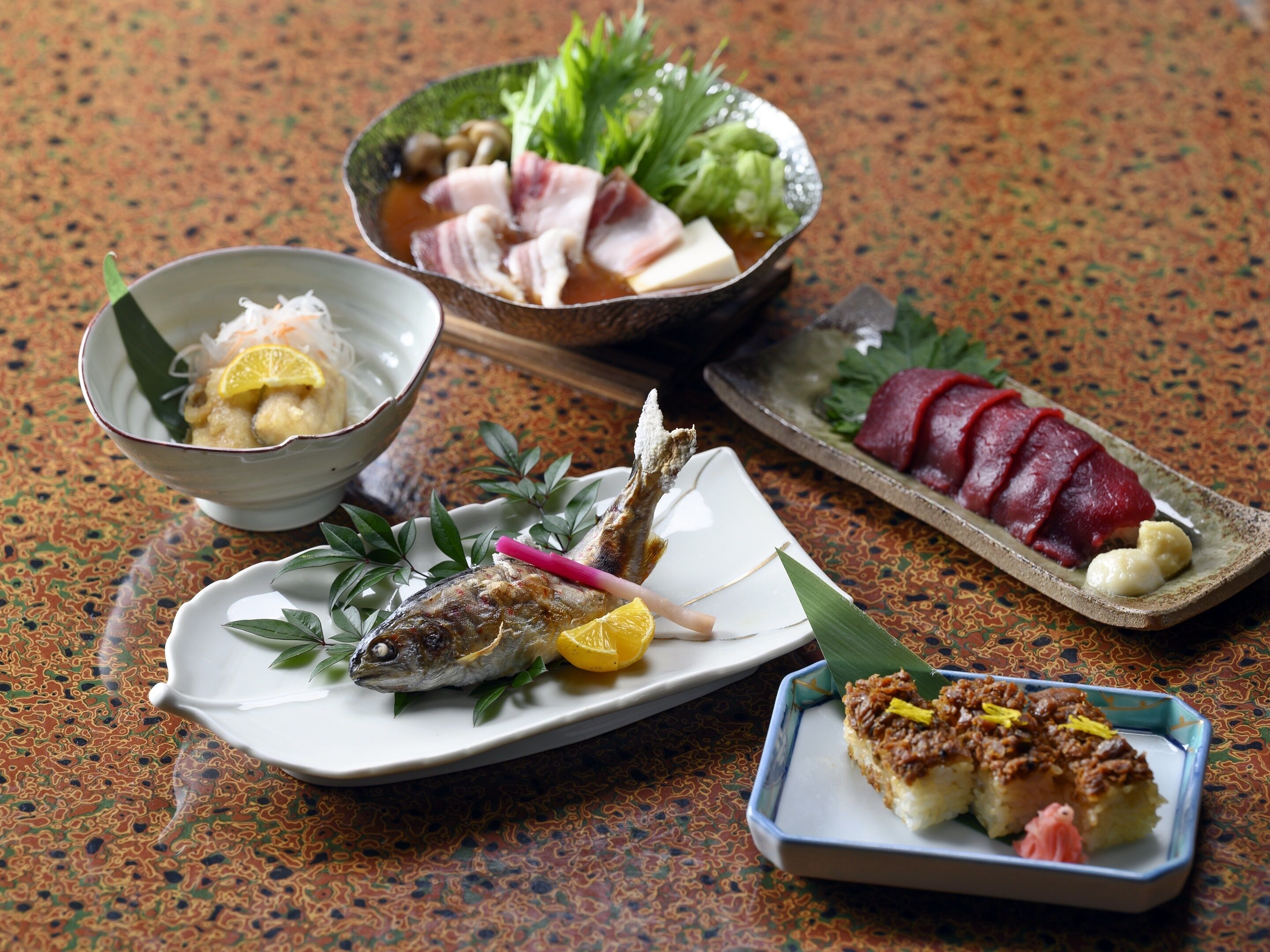 A variety of Japanese dishes including sashimi, grilled fish, and rice cakes.