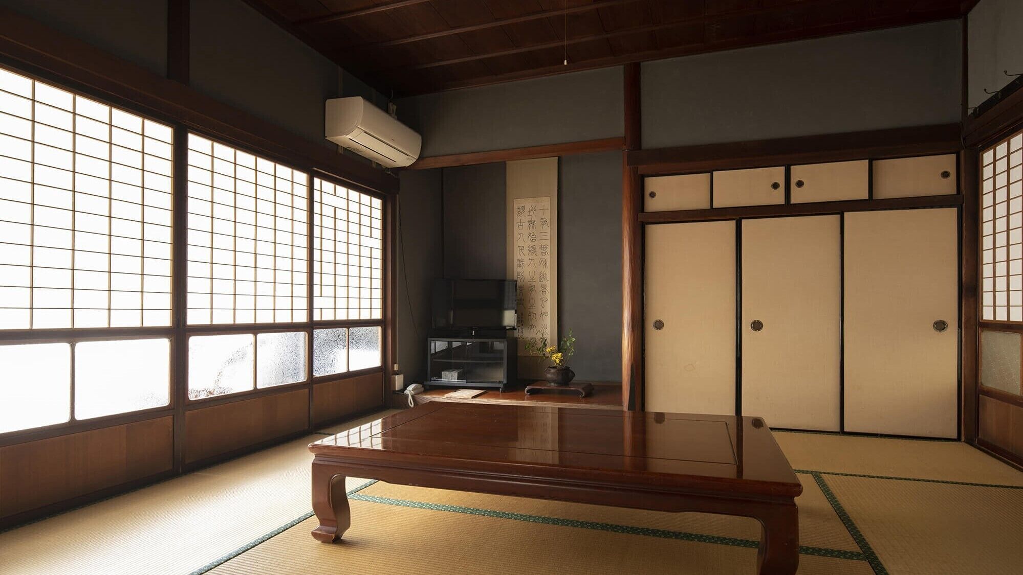 Una habitación tradicional japonesa con suelo de tatami, puertas correderas y un televisor.