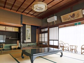 A traditional Japanese room with tatami flooring, a low table, wooden furniture, a hanging lamp, and a painting of a tiger.