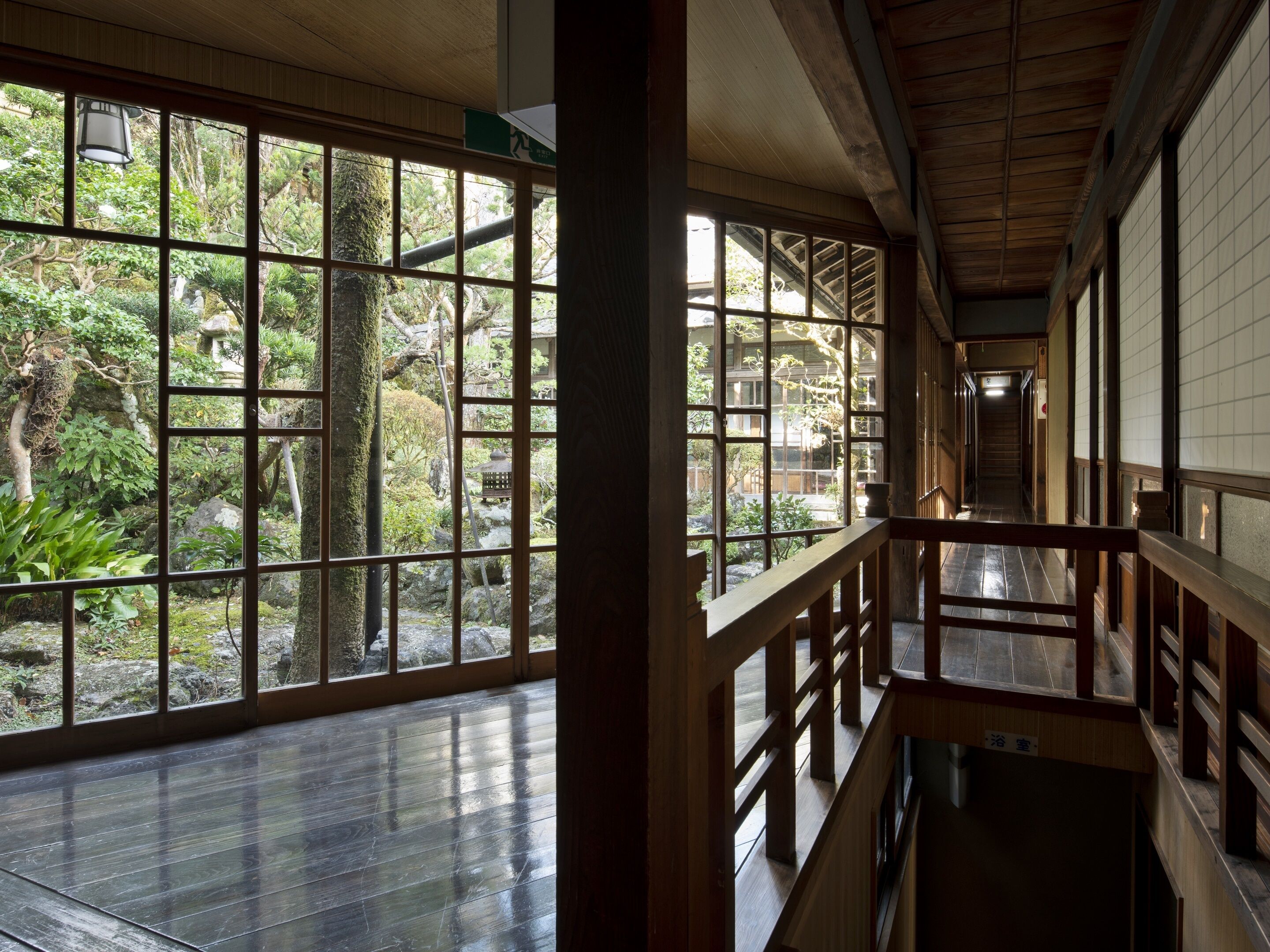 A traditional Japanese interior with wooden floors, large sliding doors, and a view of a garden.