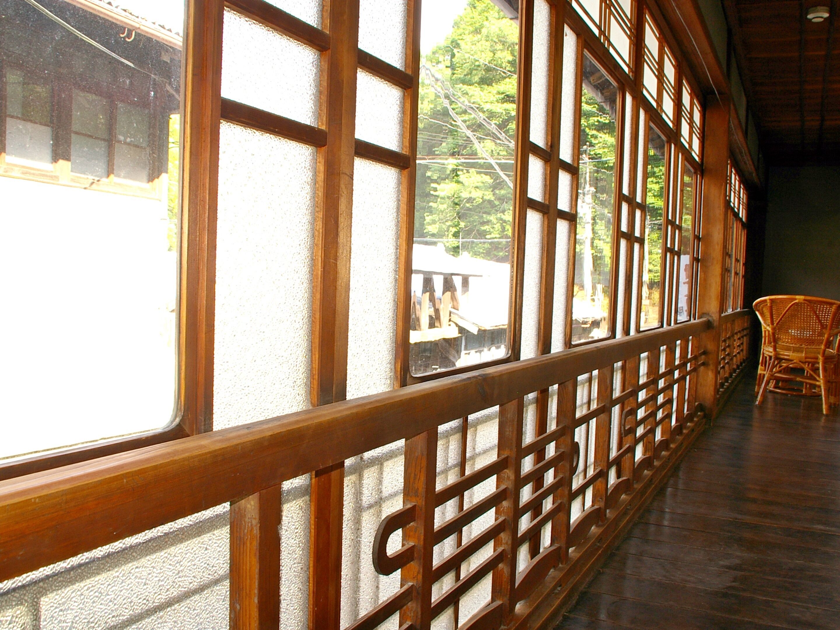 A traditional Japanese room with tatami flooring, large sliding doors, and a wooden railing.