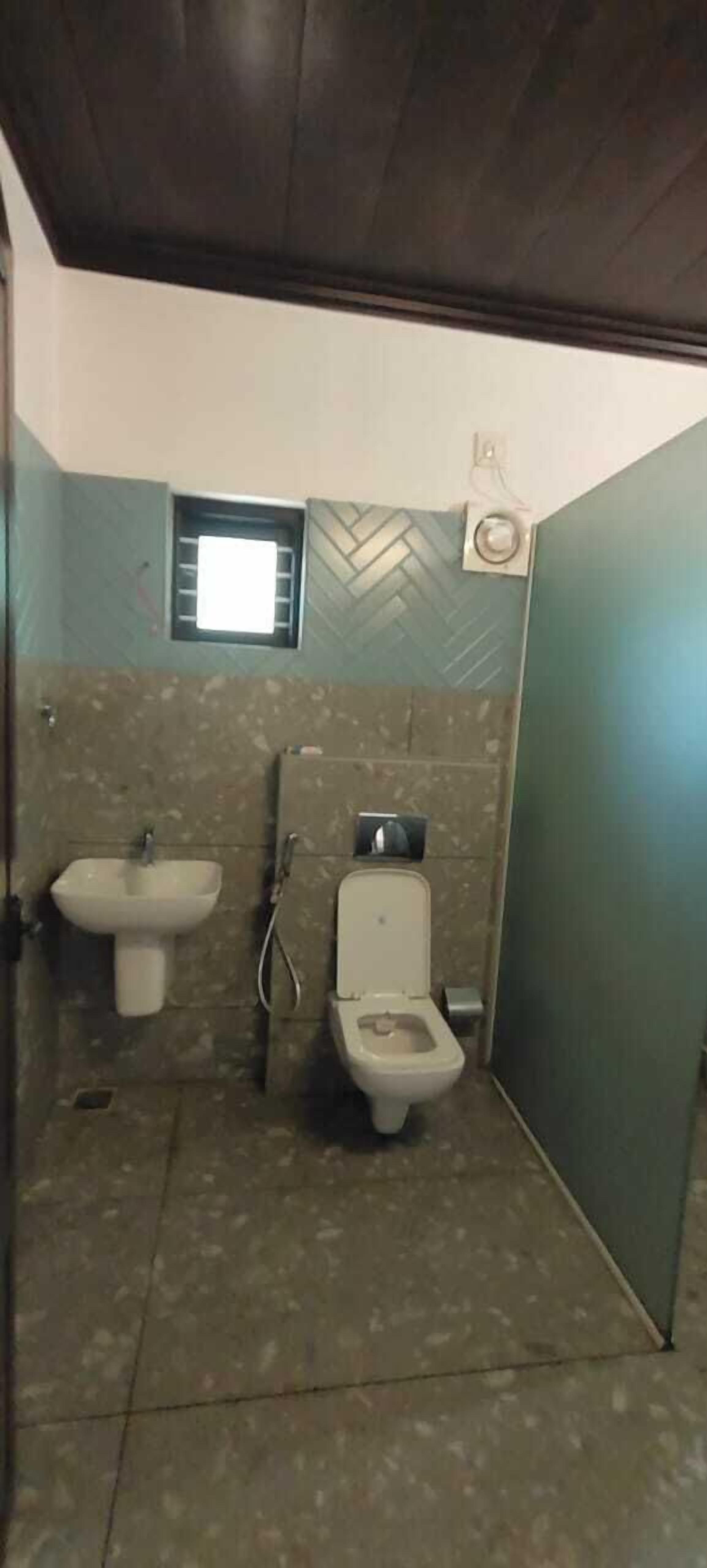Ein kleines Badezimmer mit Fliesen, Toilette, Waschbecken und Fenster.