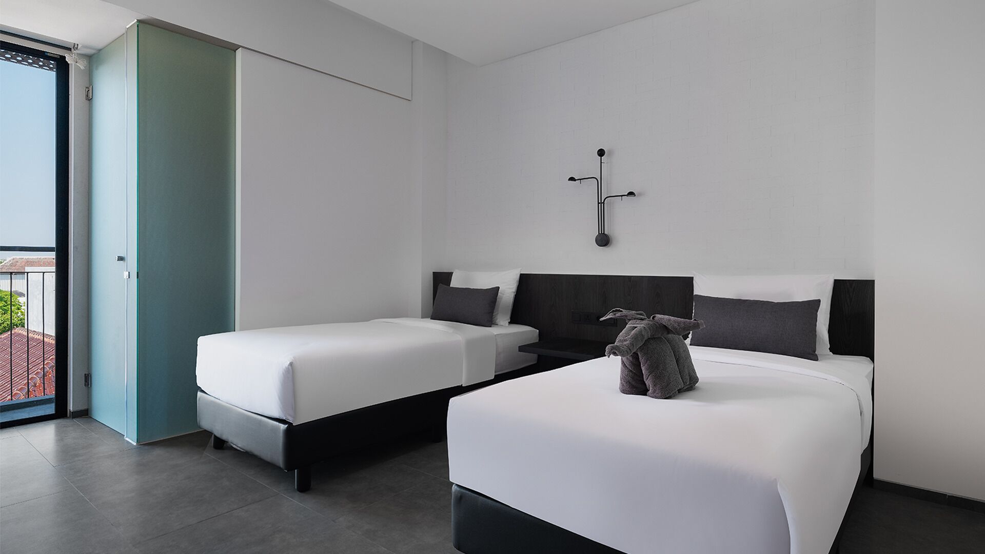 Una habitación de hotel moderna con dos camas, un ventanal grande y vistas al exterior.