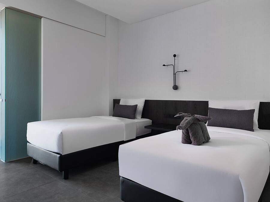 Una habitación de hotel moderna con dos camas, un ventanal grande y vistas al exterior.