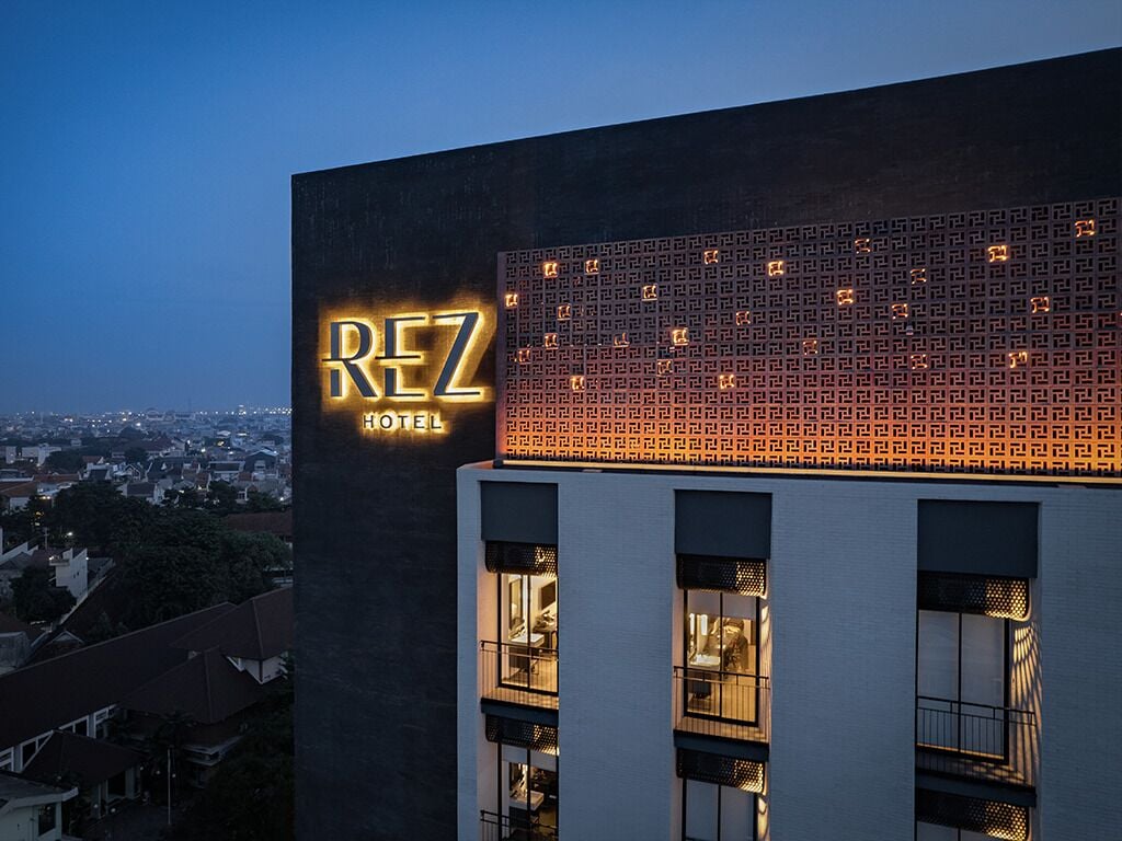 A hotel named 'REZ HOTEL' with a modern facade and illuminated signage.