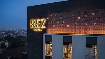 A hotel named 'REZ HOTEL' with a modern facade and illuminated signage.