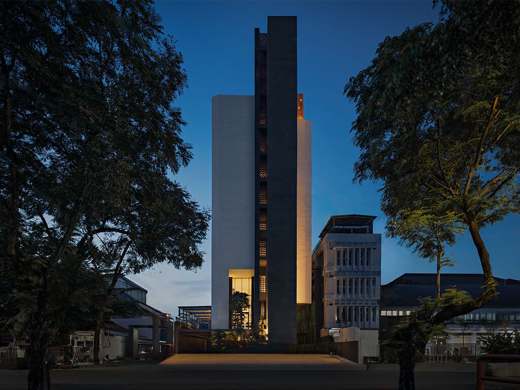 A modern building with a central tower, surrounded by trees and other structures.