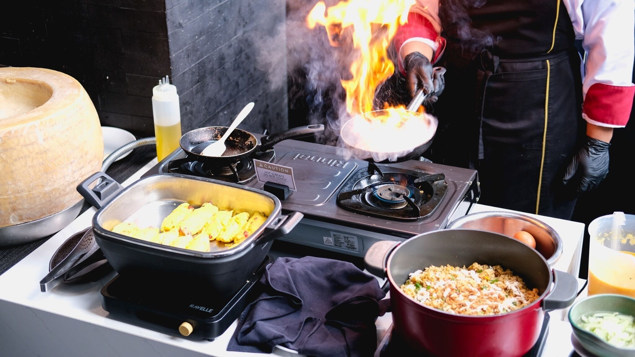 Una cocina con estufa, sartén, olla y un bol de comida.