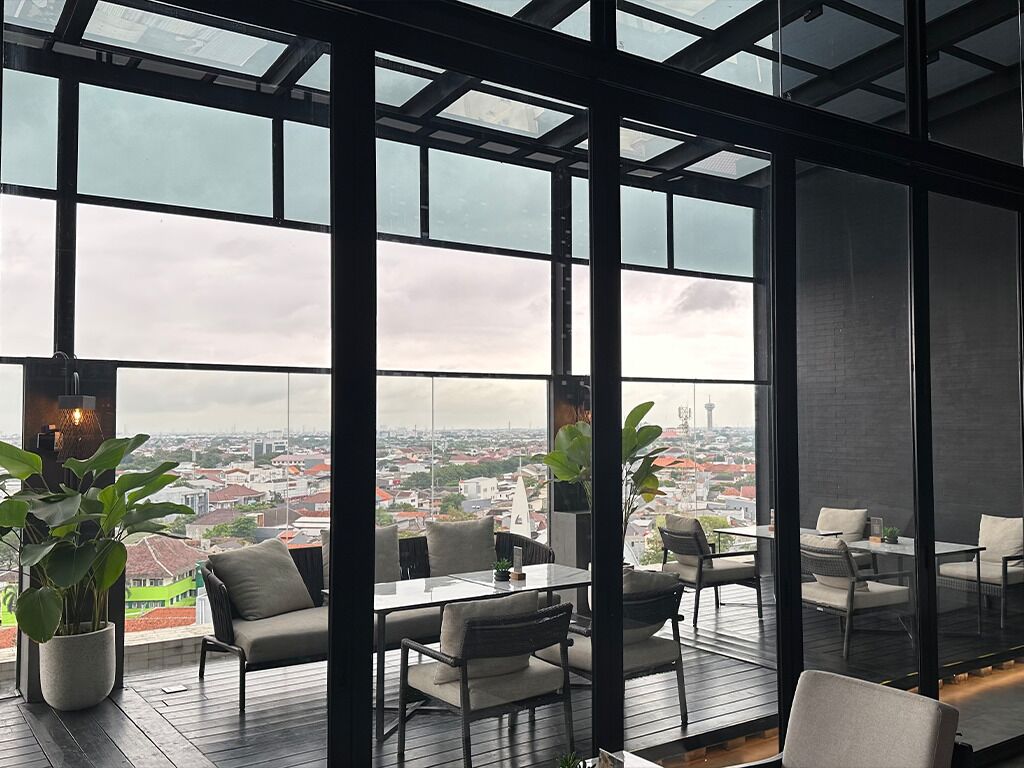 Un interior moderno con amplios ventanales, vistas a la ciudad y una zona con terraza de madera.