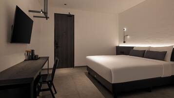 A modern hotel room with a bed, a desk, and a TV.