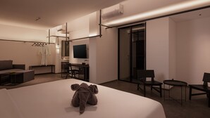 Una habitación de hotel moderna con una cama grande, un escritorio, una silla, un sofá y un televisor.