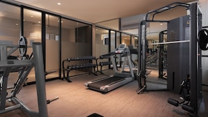 Un gimnasio moderno con equipo de cardio, máquinas de pesas y mancuernas.