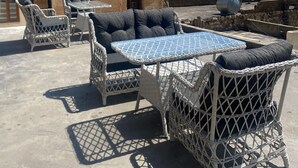 Outdoor wicker furniture with cushions, a table, and a view of a historic building with arches. - Roma Konağı Mardin (Mardin)