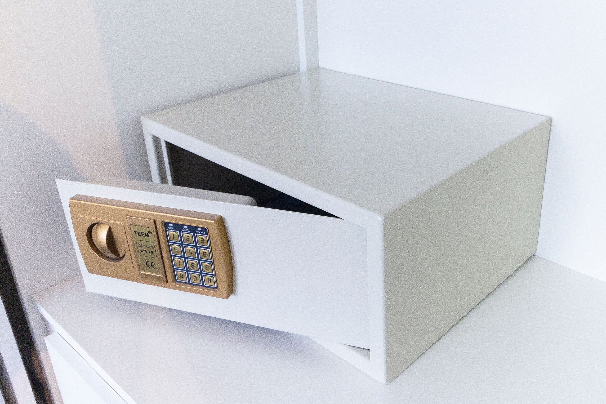 A white safe with a keypad and a gold lock.