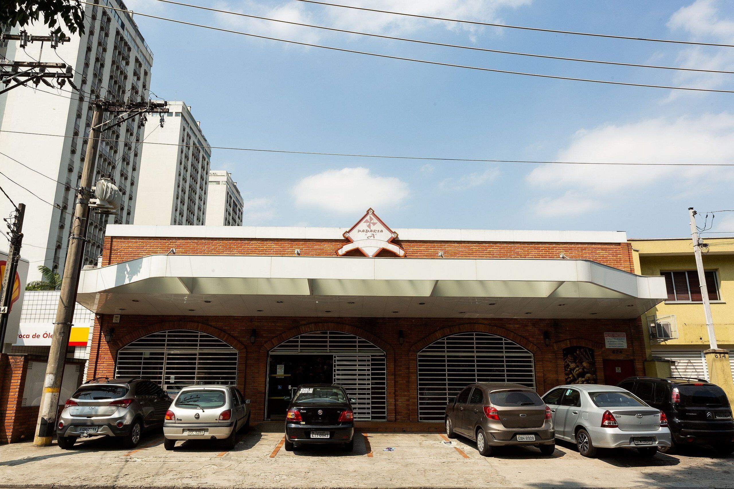 Un edificio con acceso cubierto y varios coches estacionados.