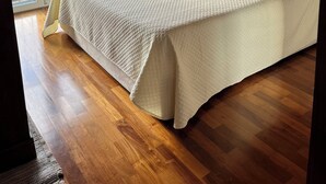 A bedroom with a wooden ceiling, a bed with a white textured bedspread, a nightstand with a lamp, and a view of a lake through a large window. - The Terrace on the lake (Fiumelatte)
