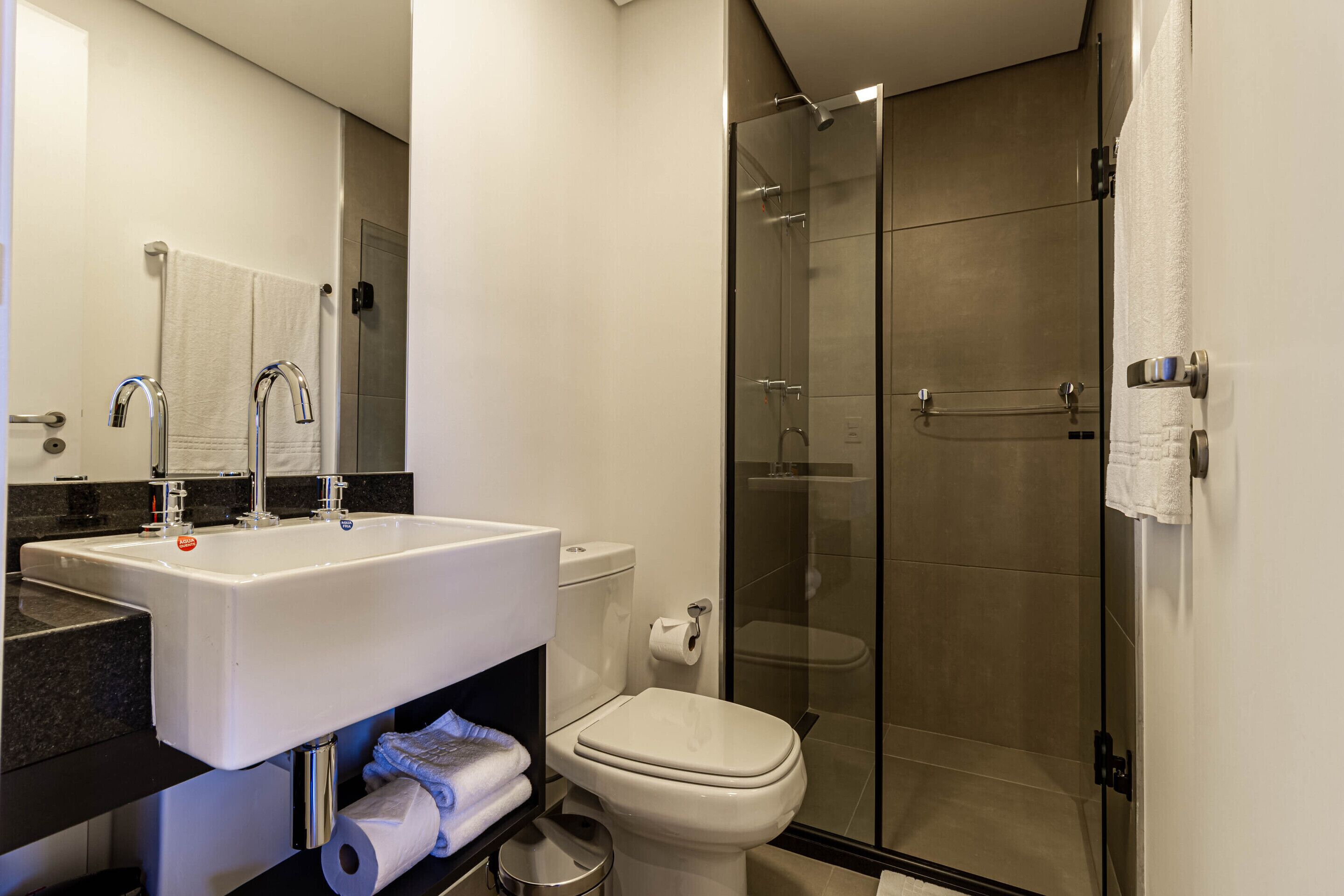 A modern bathroom with a white sink, toilet, and glass-enclosed shower.