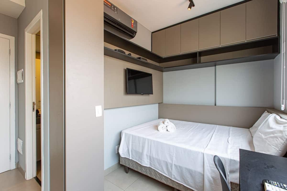 Een kleine slaapkamer met een bed, een bureau en inbouwopbergkasten.