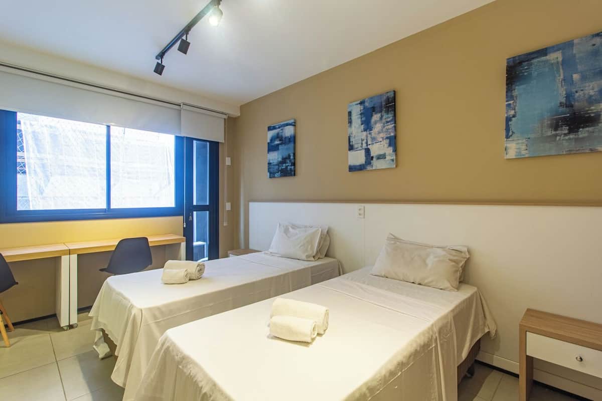 Een hotelkamer met twee bedden, een bureau en een stoel.
