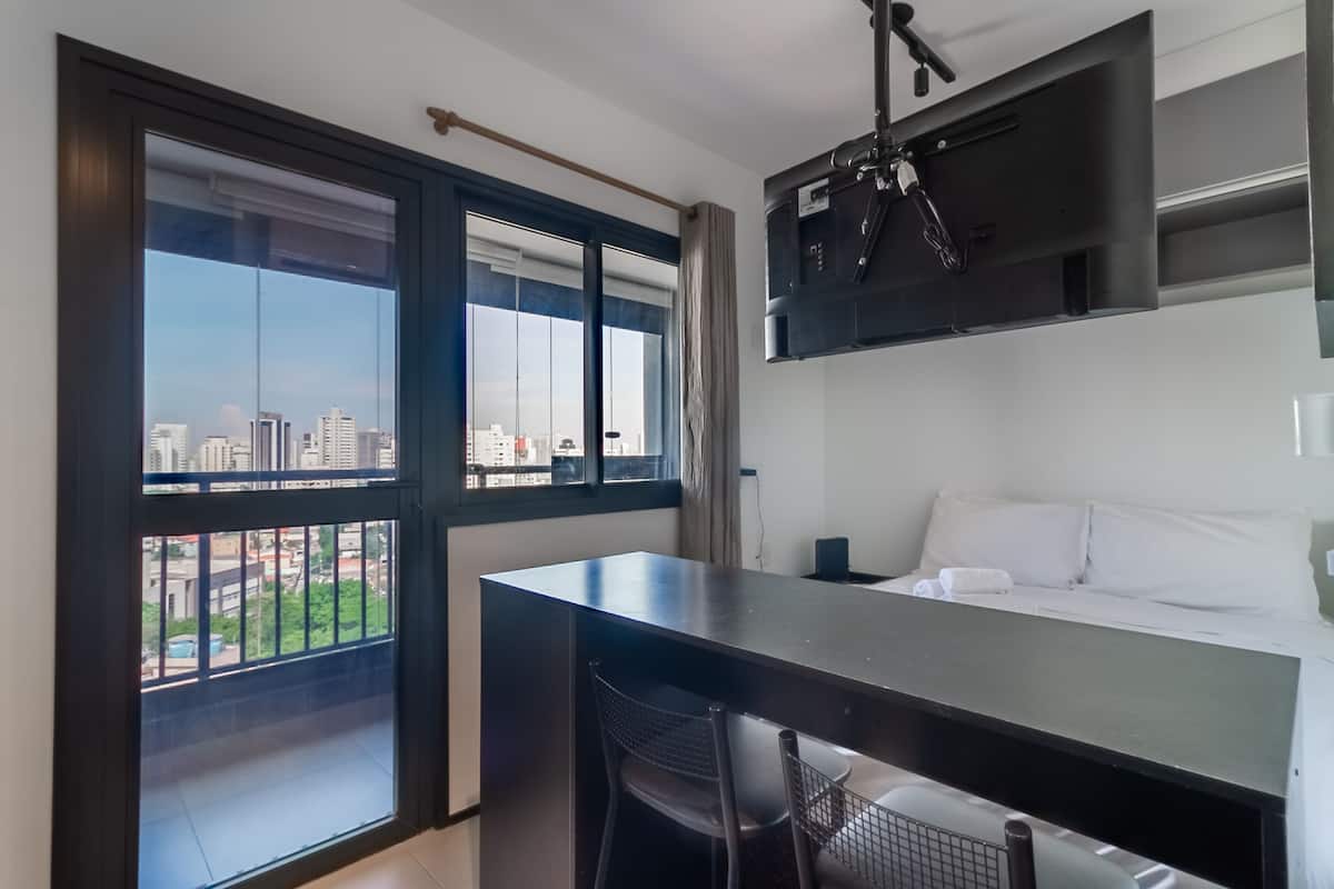 Een moderne hotelkamer met een groot raam, een zithoek en een bed.