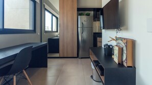 A modern kitchen with a built-in refrigerator, wooden cabinets, and a dining area with a black table and chairs. - 360 VN Humberto (São Paulo)
