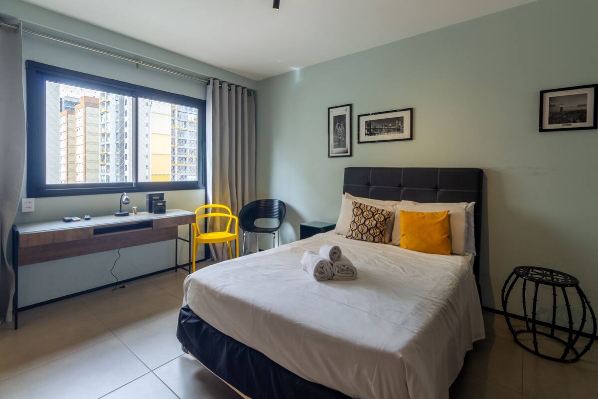 Een hotelkamer met een bed, bureau, stoel en groot raam.