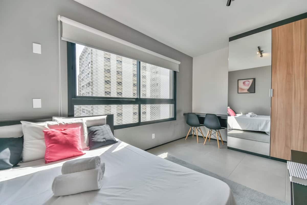 Een moderne slaapkamer met een groot bed, een bureau en een stoel.