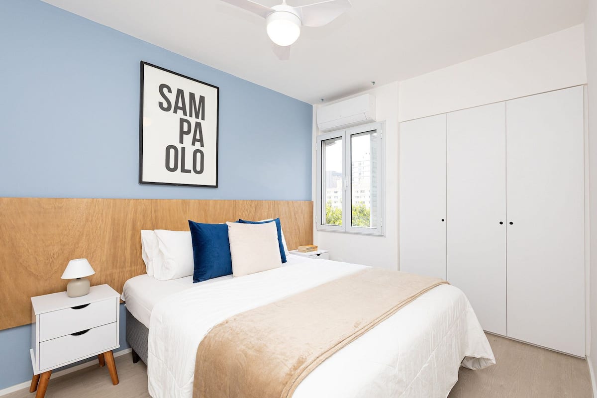 Ein Schlafzimmer mit einem Bett, einem Nachttisch, einem gerahmten Bild an der Wand, einem Fenster und einem Kleiderschrank.