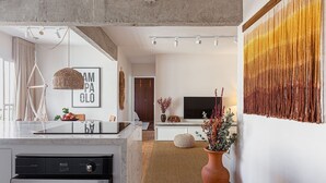 A modern kitchen with a built-in oven, a hanging light fixture, and a large vase with flowers. - Vossa Bossa Jardins (São Paulo)