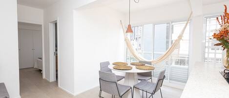 A modern kitchen with a round dining table, grey chairs, and a hanging hammock.