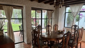 A dining area with a round wooden table, six chairs, and a chandelier. - Casa en Club de Golf (Tequisquiapan)