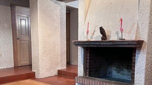 A room with a fireplace, a wooden table, and a door. - Casa en Club de Golf (Tequisquiapan)