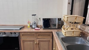 A kitchen with a stove, microwave, sink, and wooden cabinets. - Casa en Club de Golf (Tequisquiapan)