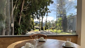 Una mesa de madera redonda con vistas a un jardín y un edificio a través de grandes ventanales.