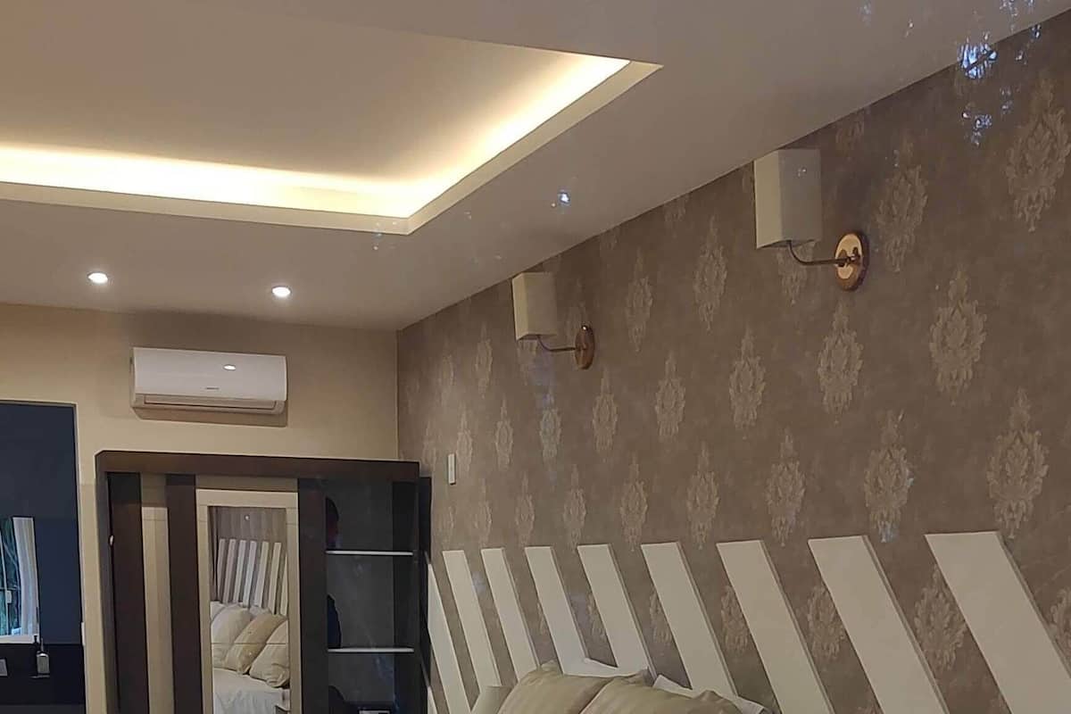 A hotel room with three beds, a wardrobe, and a mirror.