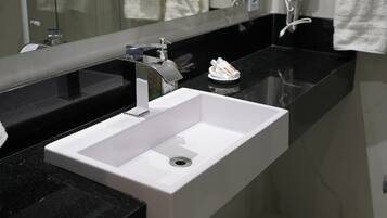 Un baño moderno con un lavamanos blanco, encimera negra y un espejo grande.