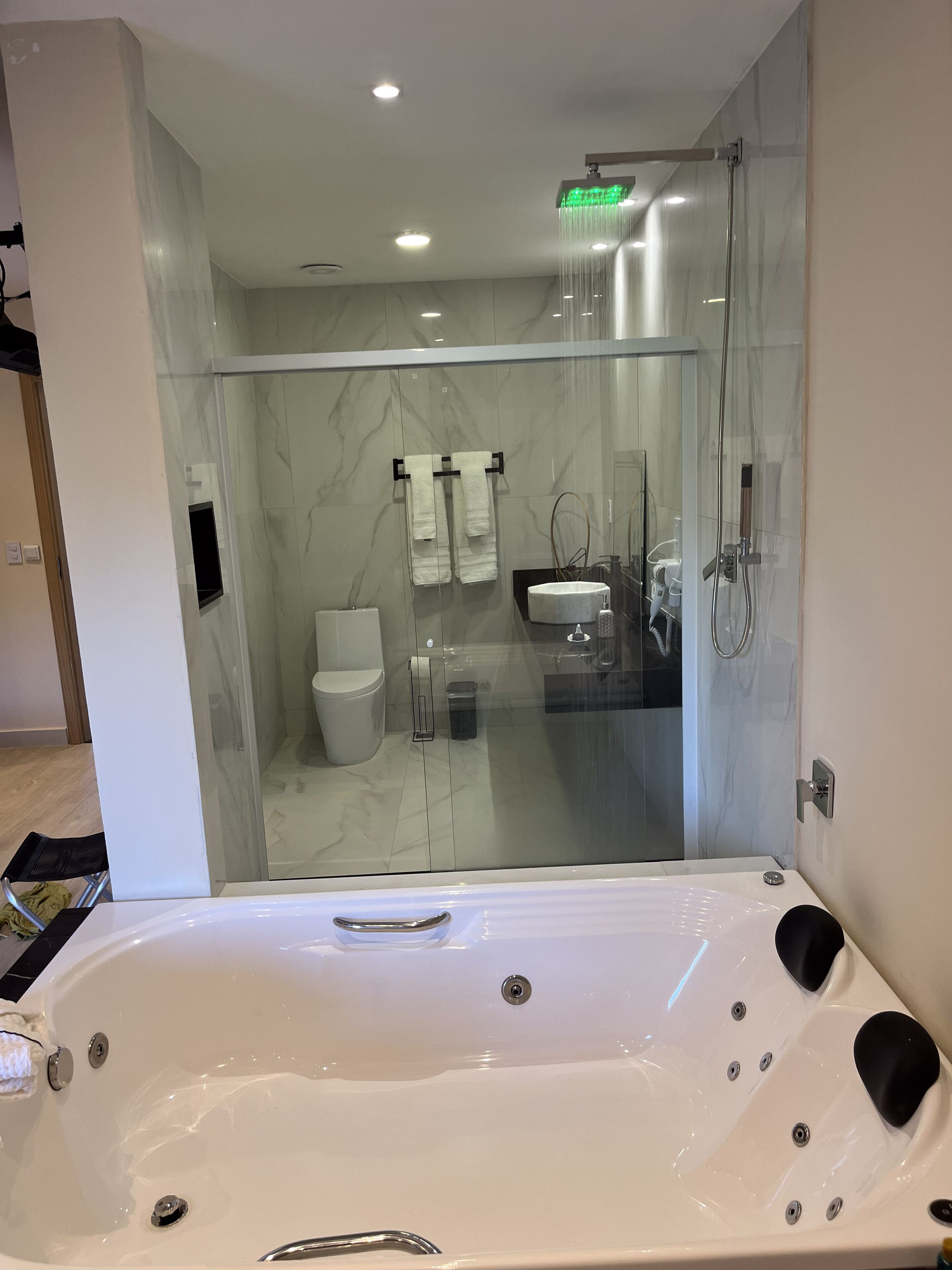 Een moderne badkamer met een douchecabine van glas, een witte badkuip en een toilet.