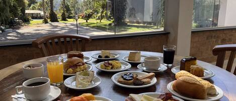 Une table de petit-déjeuner avec différents plats, une tasse de café et un verre de jus de fruits.