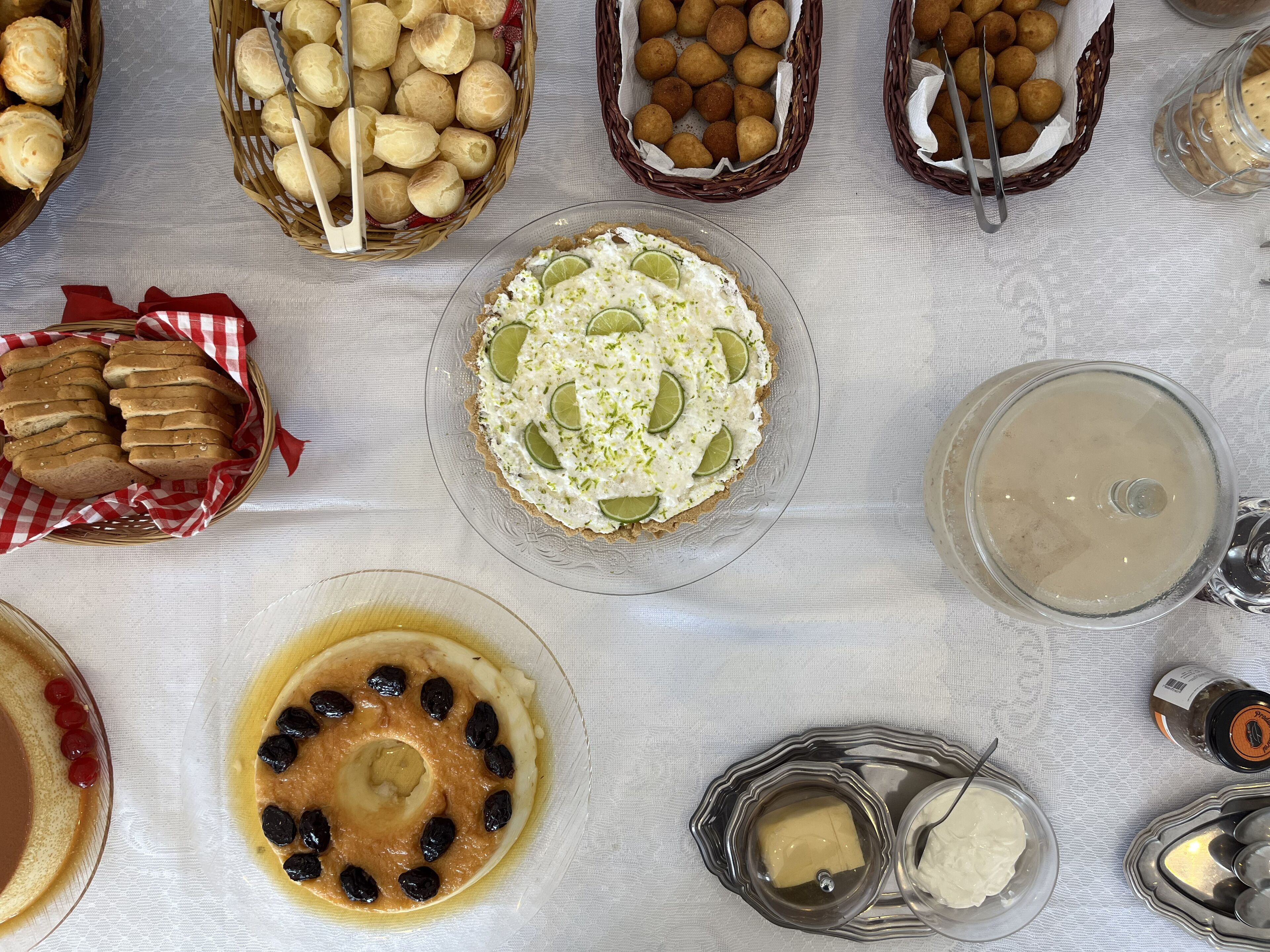 A table with various food items, including bread, pastries, and a dessert with lime slices.