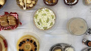 A table with various food items, including bread, pastries, and a dessert with lime slices.