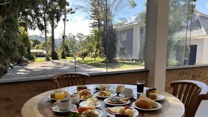 Una mesa de desayuno con diferentes platos, una taza de café y un vaso de café negro.